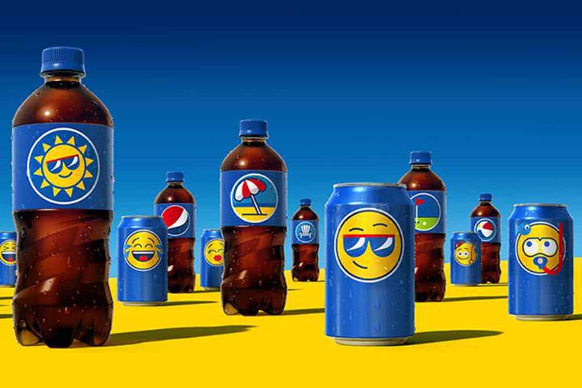 Various beverage containers, including plastic bottles and cans featuring emoji faces utilized in digital marketing, arranged on a yellow surface with a blue sky background.