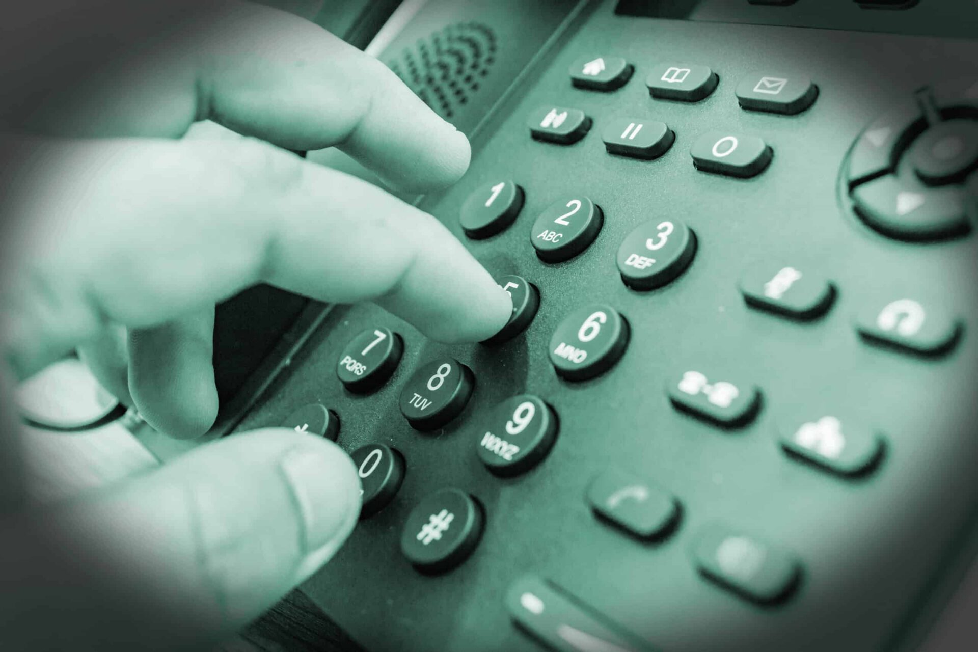 A close-up image of a person's finger pressing the number 8 on a green-tinted telephone keypad used for text message marketing.