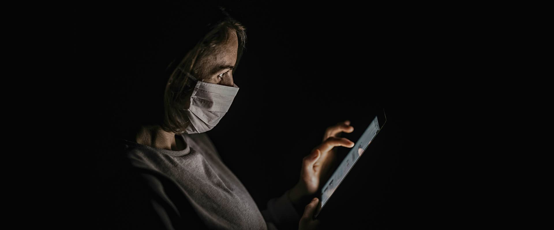 woman in mask on tablet in the dark