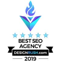 Award badge from designrush.com for "best seo agency 2019" featuring a stylized floral emblem in purple and blue, with five blue stars and a black ribbon.