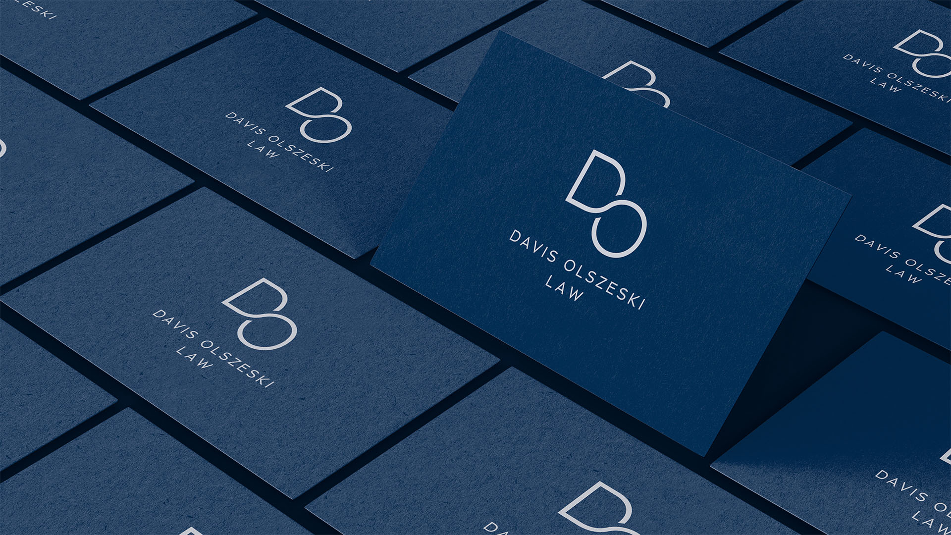 A series of business cards for Davis Olszeski Law are arranged in a tiled pattern. Each card features a minimalist white logo with the initials "DO" and the name "Davis Olszeski Law" printed below, set against a dark blue background.
